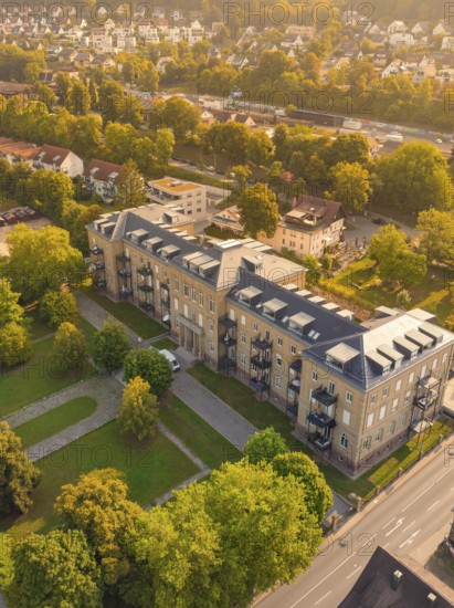 Large building with flat roof and balconies, surrounded by trees and streets in a sunny neighbourhood, small town of Perle Nagold, Black Forest, Germany