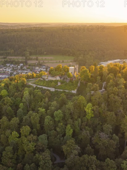Castle ruins on a wooded hill at dusk, surrounded by dense nature, small town of Perle Nagold, Black Forest, Germany