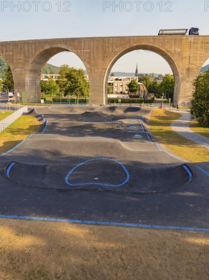 A pump track under a bridge with concrete arches and green surroundings, pump track, Nagold, Black Forest, Germany