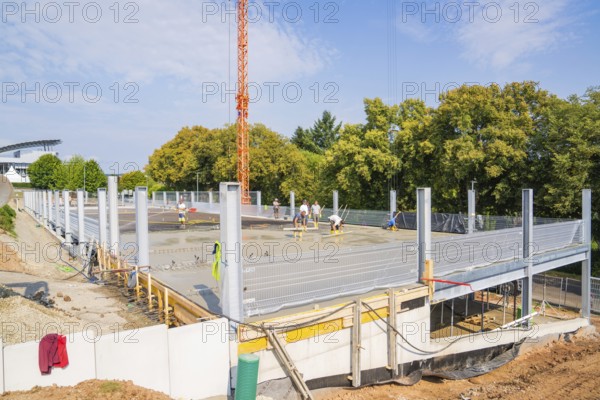 Construction site with metal structures and concrete foundation surrounded by autumnal trees, car park construction, Calw, Germany