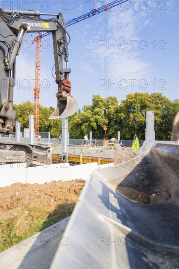 Excavator working on a construction site against a clear sky and trees in the background, car park construction, Calw, Germany