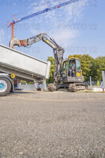 Excavator loading materials into a lorry on an asphalt road, car park construction, Calw, Germany