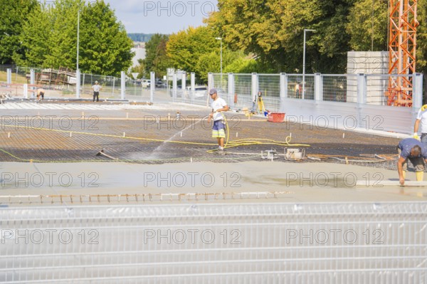 Construction workers working on the concrete surface, surrounded by trees, with safety fences, car park construction, Calw, Germany