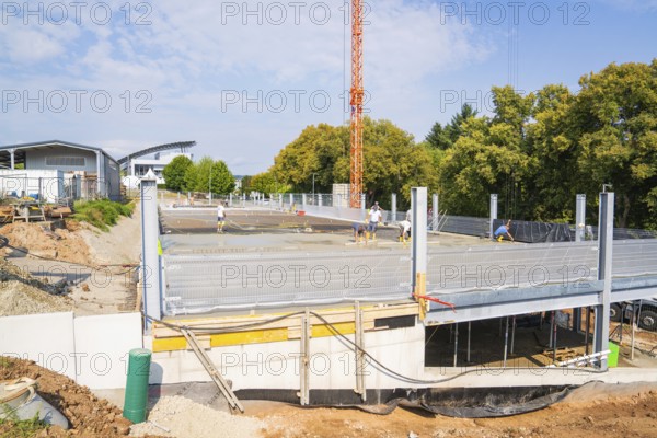 Construction site with concrete and metal structures, workers in construction clothing surrounded by autumn trees, car park construction, Calw, Germany