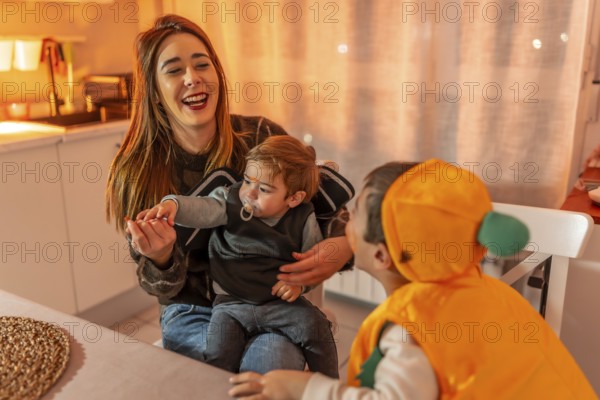 Happy mother and children dressed in festive halloween costumes enjoying fun moments together at home, filled with laughter and joy
