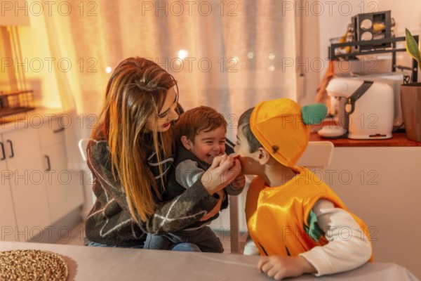 Children wearing pumpkin costumes celebrating halloween joyfully with their mother at home, creating warm memories of togetherness and laughter