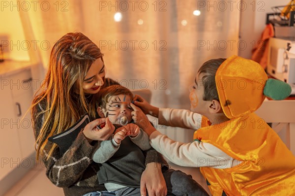 Mother and son applying halloween makeup on baby brother, getting ready for trick or treating