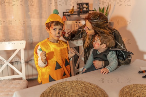 Mother painting her children's faces with halloween makeup, preparing for trick or treating