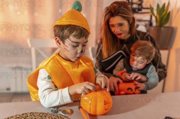 Children wearing halloween costumes are decorating pumpkin baskets with their mother at home
