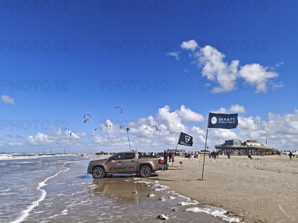 California kitesurfing Masters 2025, kitesurfing on the North Sea beach on the edge of the UNESCO World Heritage Wadden Sea, sports competition, car, pile construction, flags, strong wind, high swell, whitecaps, summer, sun, blue sky, white clouds, Ording, Sankt Peter-Ording, Schleswig-Holstein, Germany