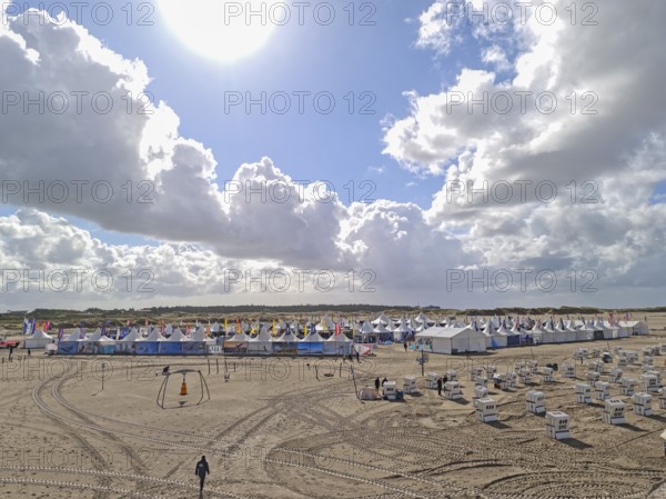 California kitesurfing Masters 2025, tents of the Kite Village with kite equipment for sale, marketplace, try out, kitesurfing on the North Sea beach, blue sky, sun, summer, backlight, Ording, Sankt Peter-Ording, Schleswig-Holstein, Germany