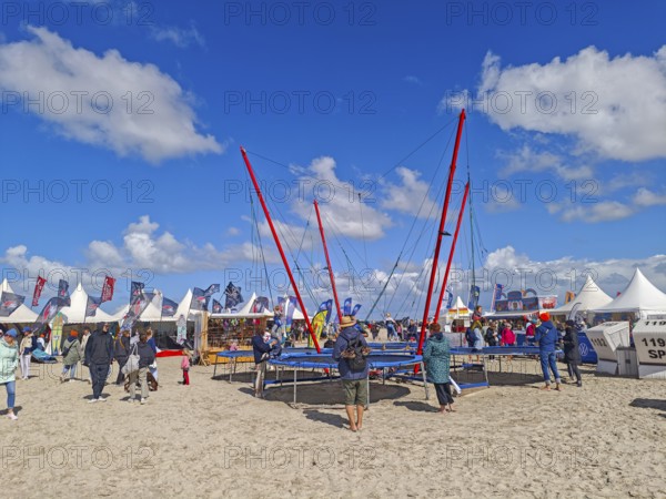 California kitesurfing Masters 2025, Kite Village tents with kite equipment for sale, marketplace, try out, kitesurfing on the North Sea beach, blue sky, sun, summer, trampoline, Ording, Sankt Peter-Ording, Schleswig-Holstein, Germany