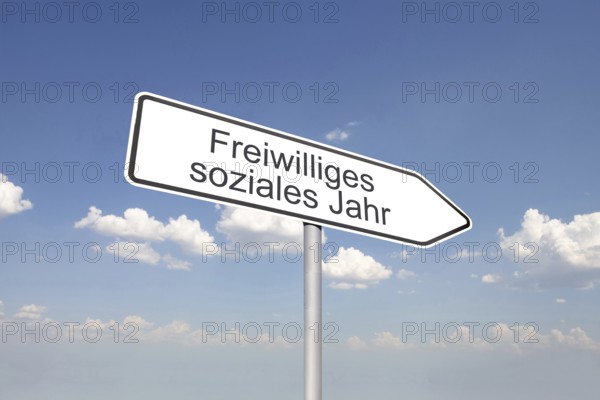 (Photomontage) Directional arrow with the inscription VOLUNTARY SOCIAL YEAR against a blue sky