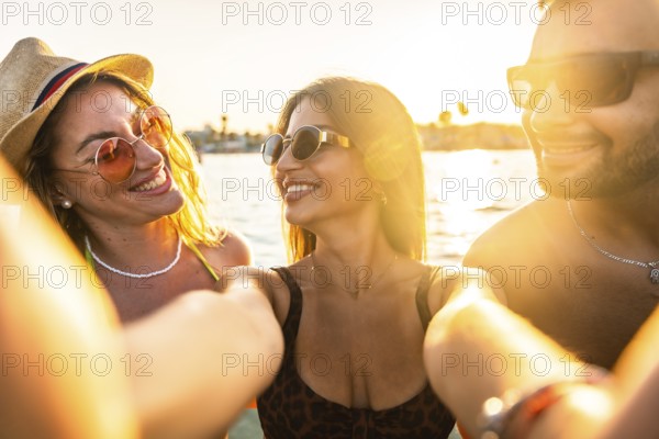 Group of friends enjoying a scenic boat trip, capturing joyful selfies against a stunning sunset backdrop, celebrating summer together