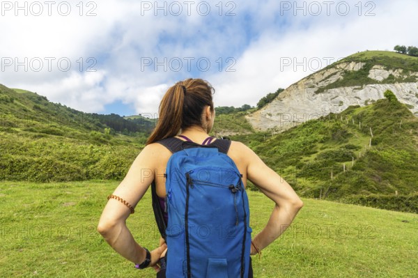Female hiker admiring the breathtaking view of the sakoneta beach and flysch cliffs in zumaia, gipuzkoa, basque country