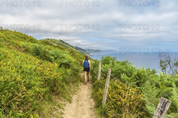 Female tourist enjoying a picturesque hike along the cliffs leading to sakoneta beach in zumaia, gipuzkoa, appreciating the breathtaking view of the bay of biscay