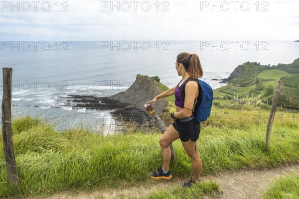 Female hiker admiring the impressive flysch cliffs and coastline of sakoneta beach in zumaia, gipuzkoa, basque country, spain