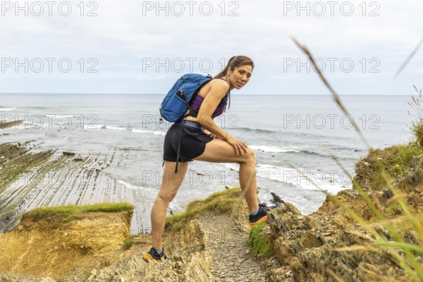Female hiker enjoying the scenic view of the sakoneta beach and flysch cliffs in zumaia, basque country, spain