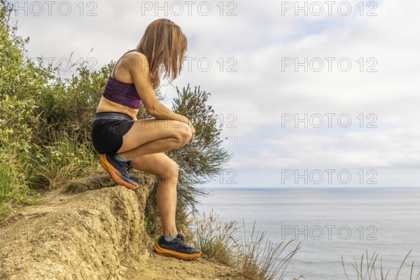 Female athlete taking a break from her training, enjoying the breathtaking scenery of sakoneta beach and the flysch cliffs in zumaia, basque country