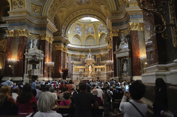 Tourists and locals are attending a mass in st. Stephen's basilica, a romanesque catholic basilica in budapest, hungary