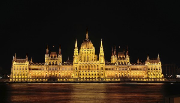 Majestic hungarian parliament building glowing gold at night, reflected in the danube river, budapest, hungary