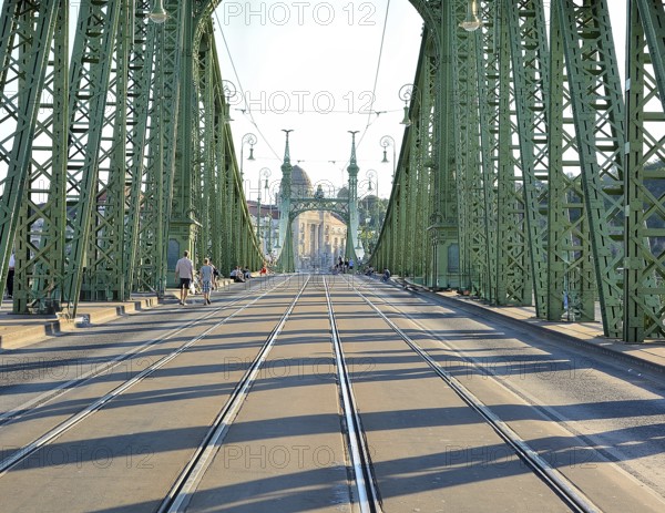 Tourists walking on liberty bridge in budapest, hungary, on a sunny day, with its iconic green steel structure