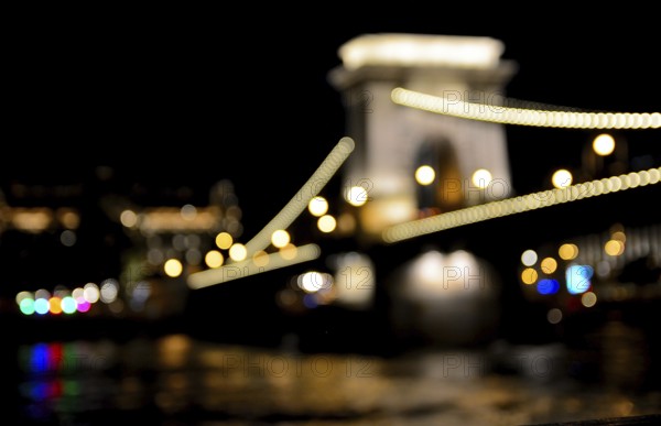 Blurred lights highlighting the chain bridge in budapest, hungary at night, reflecting in the danube river, creating a magical atmosphere
