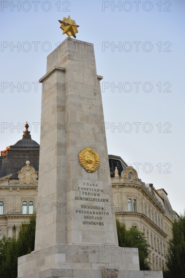 Soviet war memorial with golden star and hammer and sickle emblem standing tall against clear sky in budapest, hungary