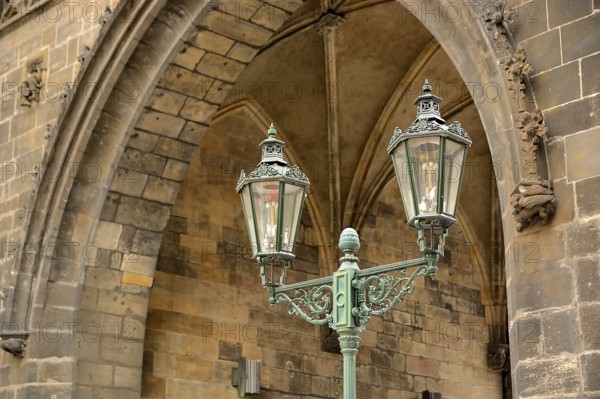 Ornate gas lamp stands beneath a stone arch, showcasing the city's rich history and craftsmanship