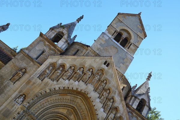 Low angle view of jaki chapel facade showing stone statues of saints and bell tower in budapest, hungary
