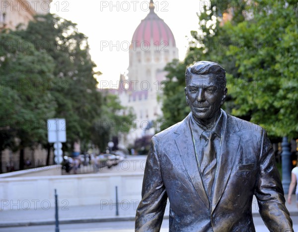 Bronze statue of former us president ronald reagan welcomes visitors to szabadsag ter in budapest, hungary, with the hungarian parliament building in the distance