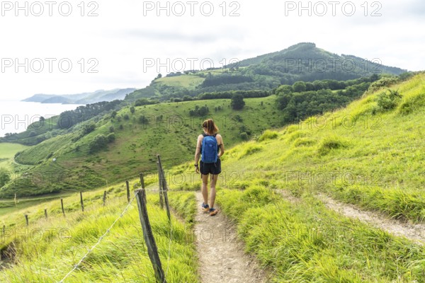 Tourist with backpack enjoying a hike in the basque country near sakoneta beach and its flysch in zumaia, gipuzkoa