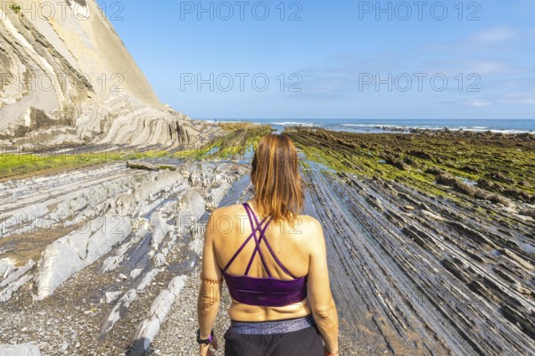 Female tourist exploring the unique geological formations of the flysch cliffs on sakoneta beach in zumaia, gipuzkoa, a popular travel destination in the basque country