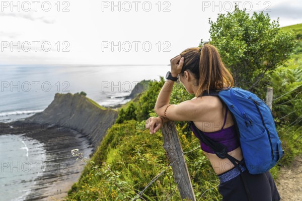 Female hiker enjoying the scenic view of the sakoneta beach and its coastal flysch in zumaia, gipuzkoa