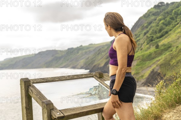 Sportswoman enjoying the view of the sakoneta beach area and its coastal flysch in zumaia, gipuzkoa