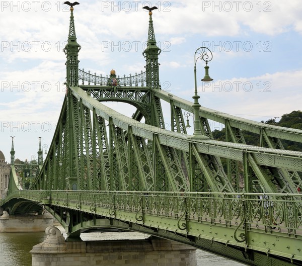 Liberty bridge, a green steel bridge, is standing over danube river in budapest, hungary, connecting buda and pest