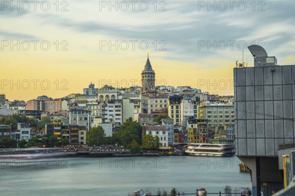 Galata tower rising above colorful buildings along the golden horn in istanbul, turkey, during a vibrant sunset