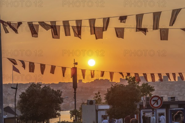 Capturing an orange sunset illuminating the istanbul cityscape, with turkish flags gracefully waving in the evening breeze
