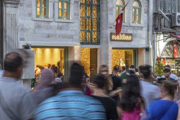 People walking on the street in front of a busy restaurant in istanbul, turkey, in motion blur