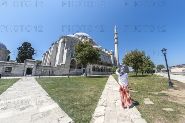 Tourist capturing stunning images of suleymaniye mosque in istanbul on a bright, sunny summer day, surrounded by vibrant city life