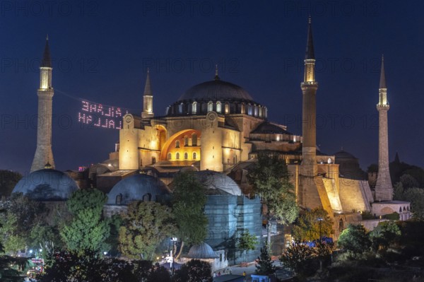 Hagia sophia illuminated at night with a drone light show displaying a religious message in the sky above istanbul, turkey