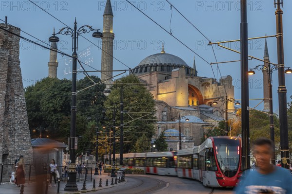 Modern tram passing in front of the ancient hagia sophia mosque in istanbul, turkey, during a beautiful sunset