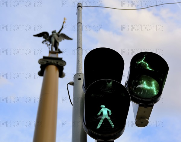 Green traffic light allows pedestrians to cross the street in budapest, hungary, with a statue visible in the background
