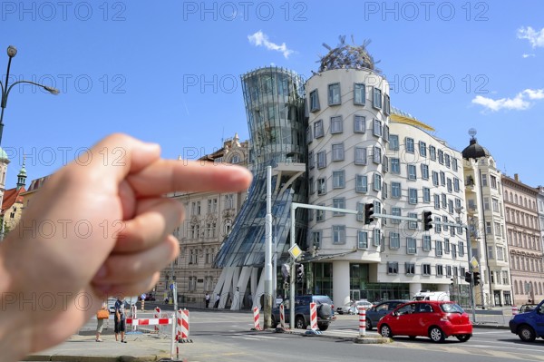 Hand pointing at the famous dancing house in prague, czech republic, a deconstructivist office building also known as fred and ginger