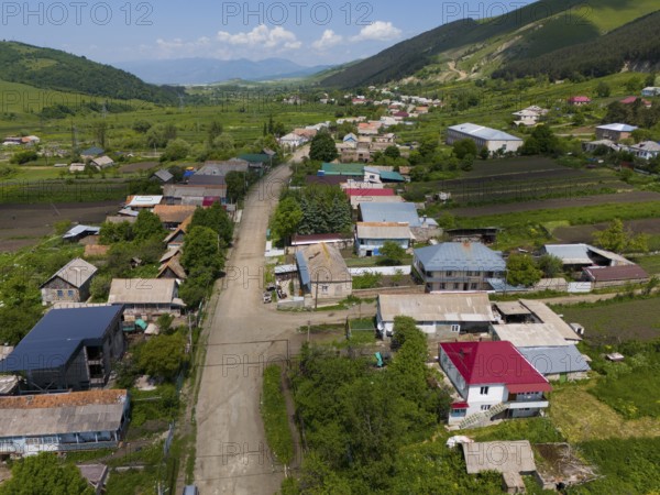 Village view with several houses, surrounded by green hills and a winding road, aerial view, Lermontovo, inhabited by spiritual Christians Pryguny and Molokans from Russia, Lorikeet Province, Armenia