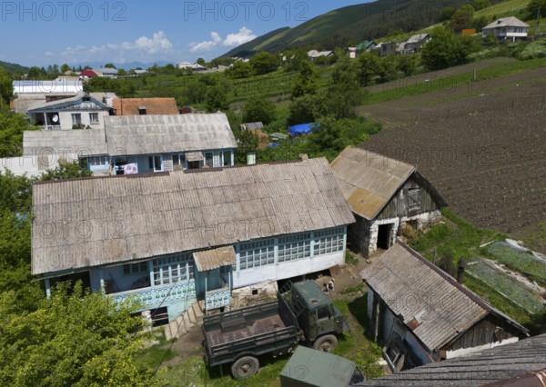 Tractors and implements in a rural setting with fields and mountains in the background, aerial view, Lermontovo, inhabited by spiritual Christians Pryguny and Molokans from Russia, Lorikeet Province, Armenia