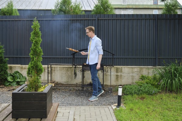 In a vibrant backyard garden, a man stands next to a grill, skillfully cooking skewered food. Lush greenery surrounds the outdoor space, creating a lively atmosphere during a sunny afternoon