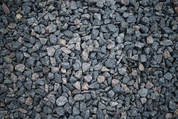 A close-up view of dark gravel featuring small, irregularly shaped stones in shades of gray and hints of pink