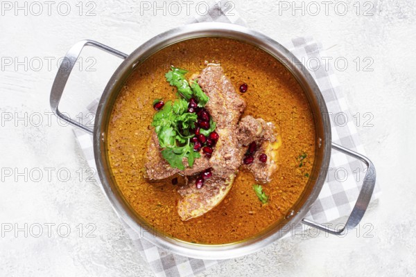 Fesenjan, an Iranian dish, stewed chicken, in a nut-pomegranate sauce, in a saucepan, light background, homemade, no people