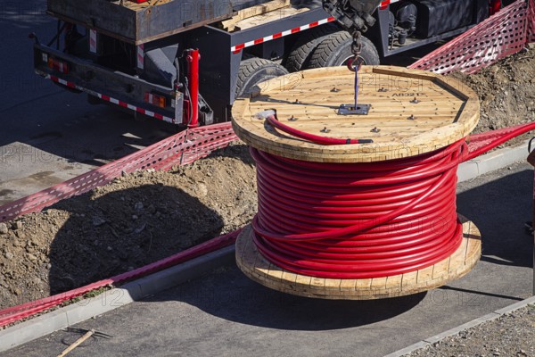 Big red cable coil, rises for installation at the city construction site, no people